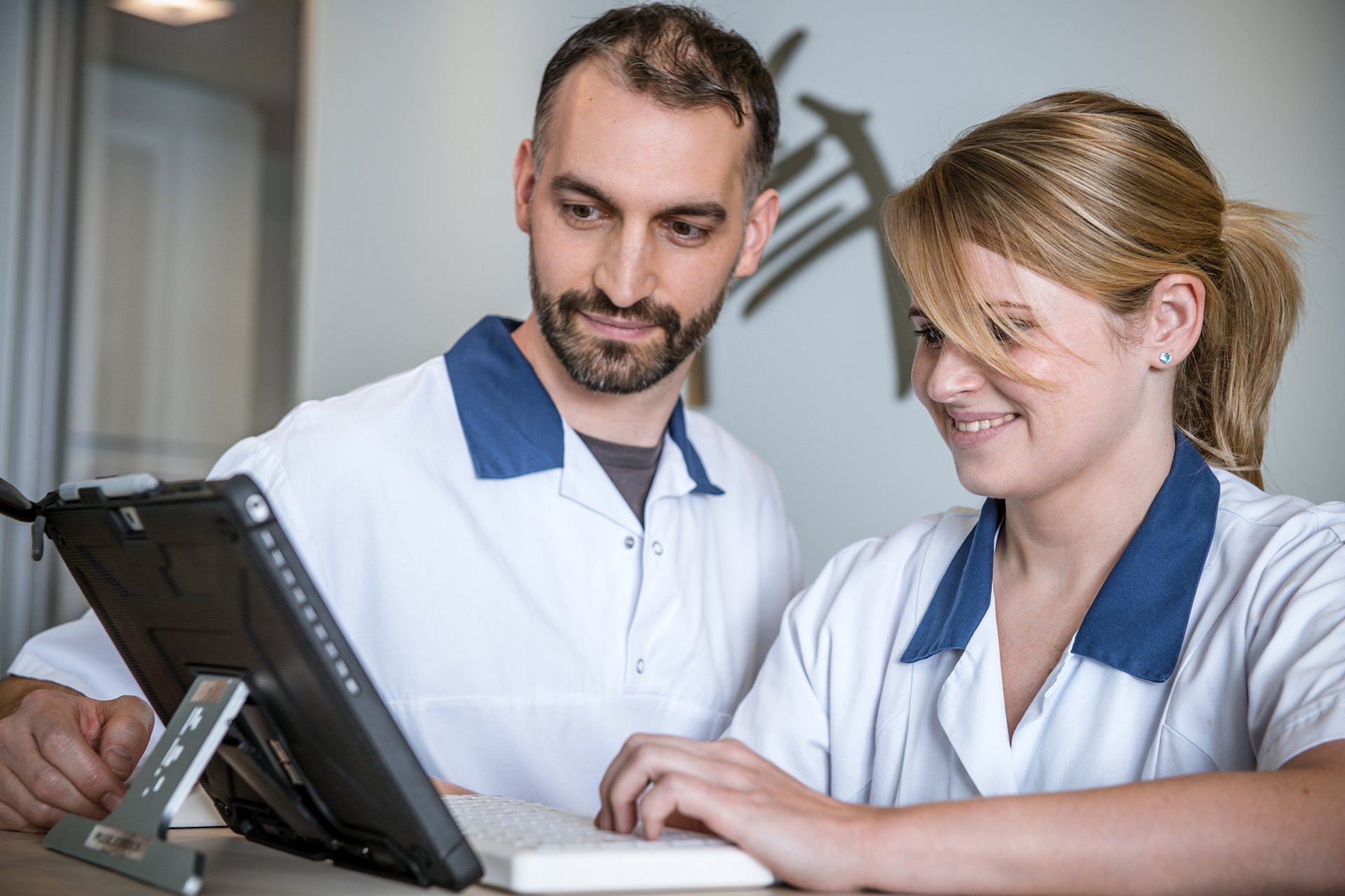Pflegefachmann und Pflegefachfrau schauen gemeinsam in einen Laptop