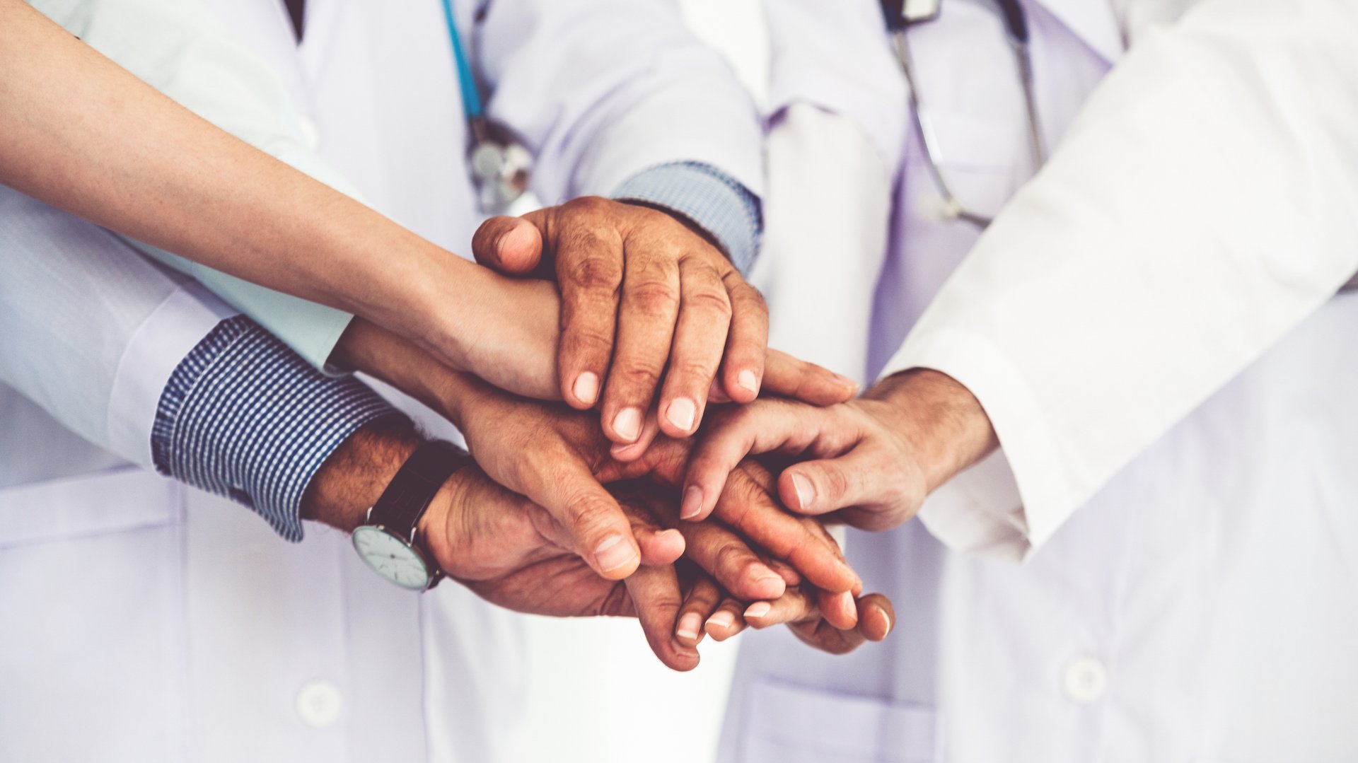 Hände von vier Ärzten übereinander