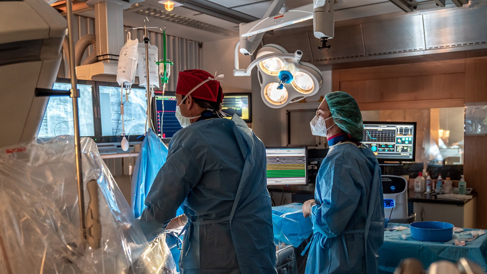 Ein Arzt und eine Ärztin führen eine Herzschrittmacheroperation in einem hochmodernen Linksherzkatheterlabor durch